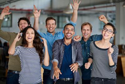 group of happy fun people in a room with their hands up